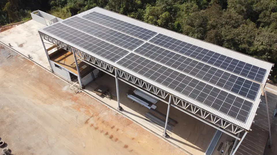 Vista aérea do galpão industrial em Congonhas com módulos solares na cobertura metálica