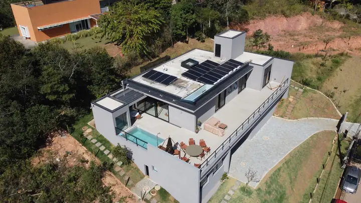 Vista aérea de residência moderna em Nova Lima com módulos solares sobre a laje